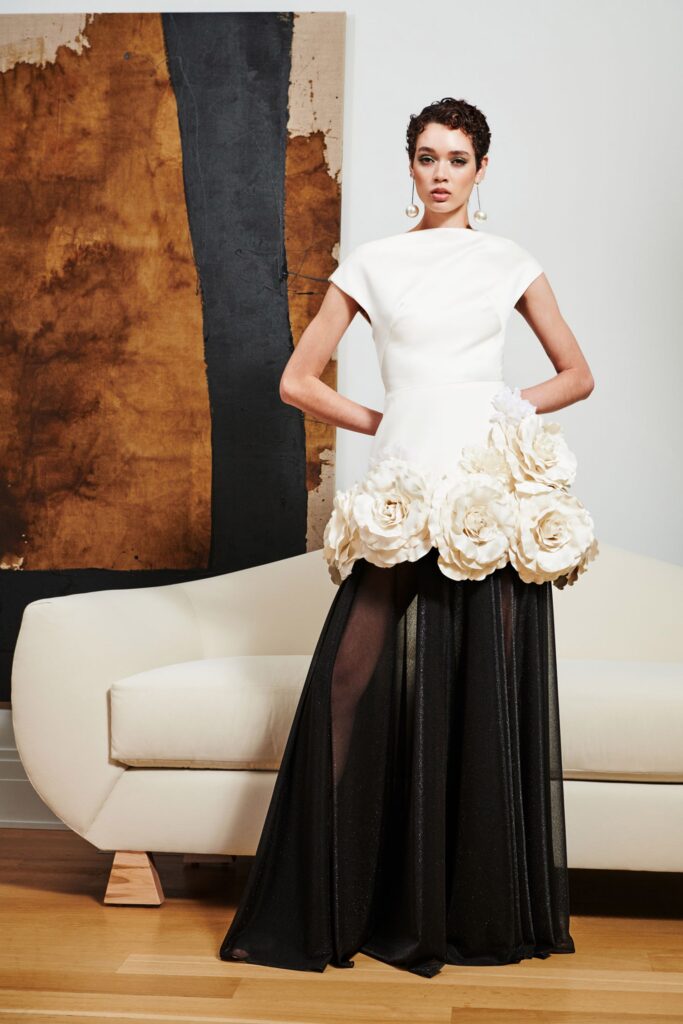 A fitted black and white dress with a high neckline and layered, flared design.