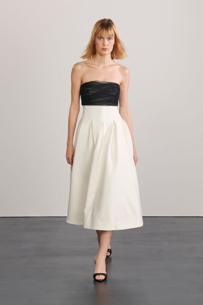 A fitted black and white strapless dress with pleated detailing.