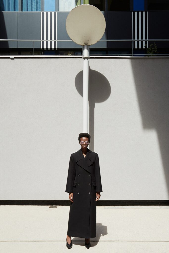 A fitted black wool coat with long sleeves and a double-breasted design.