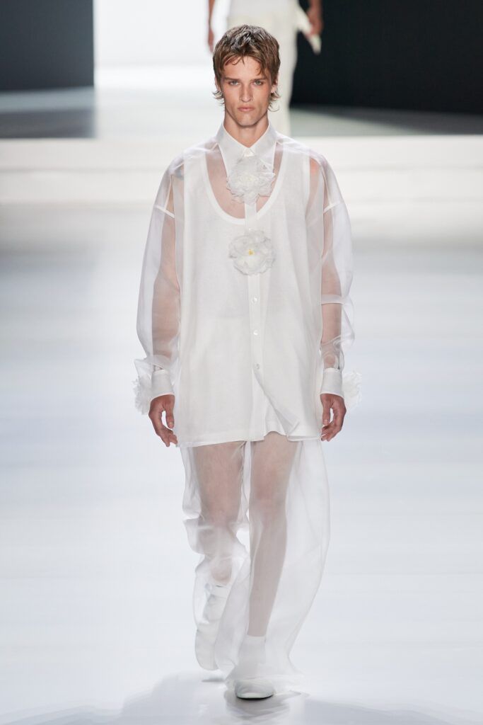 A relaxed white sheer long-sleeve shirt with a collared neckline and layered design paired with matching pants.