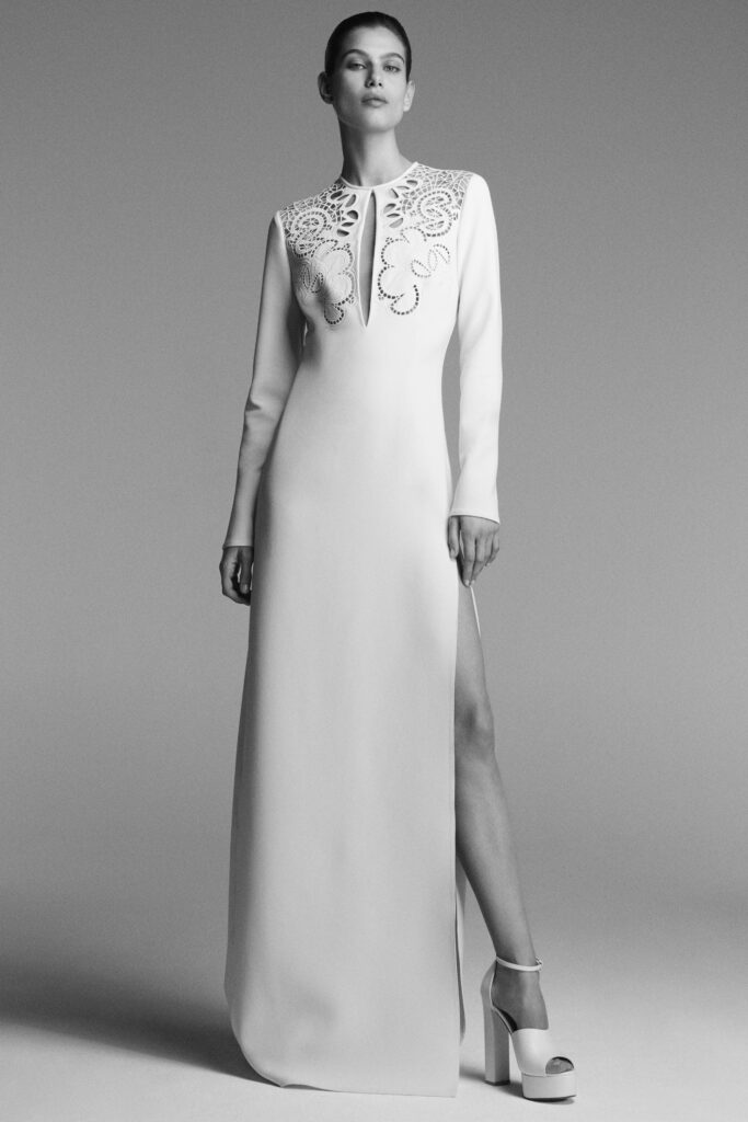 A fitted white silk dress with long sleeves, a V-neckline, and a side slit.