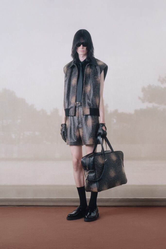 A fitted black leather sleeveless vest paired with matching printed shorts.