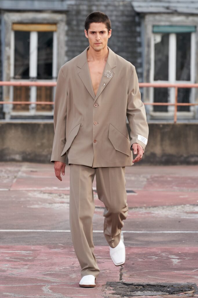 A relaxed beige cotton suit with a collared long-sleeve jacket and buttoned details.