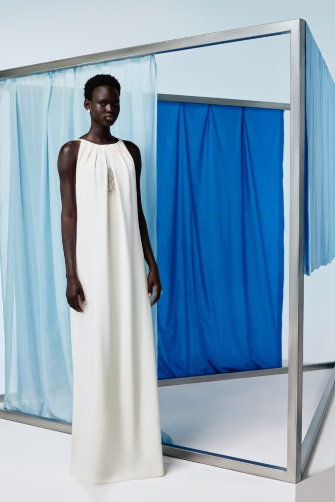 A relaxed white silk sleeveless gown with a high neckline and flowing silhouette.