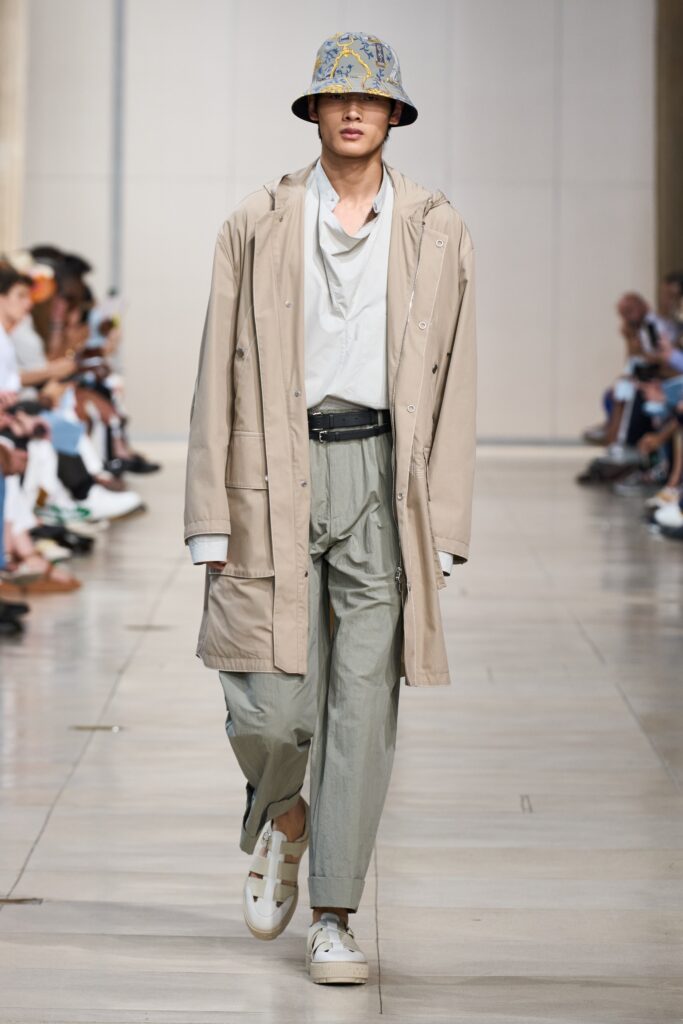 A relaxed beige coat paired with wide-leg gray pants and a collared shirt.