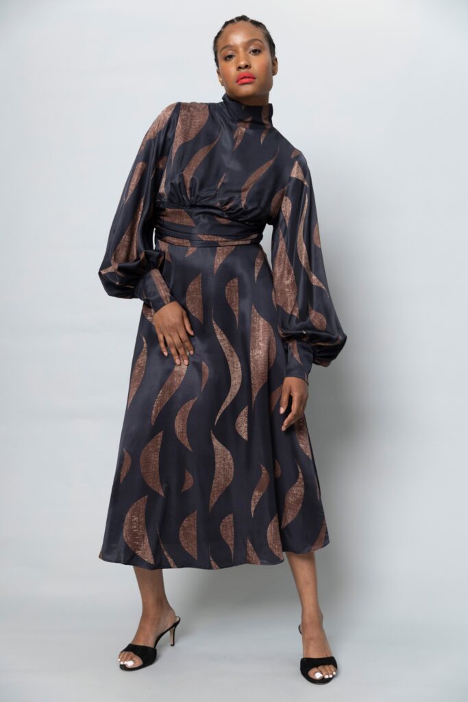 A fitted black and brown printed dress with long sleeves and a high neckline.