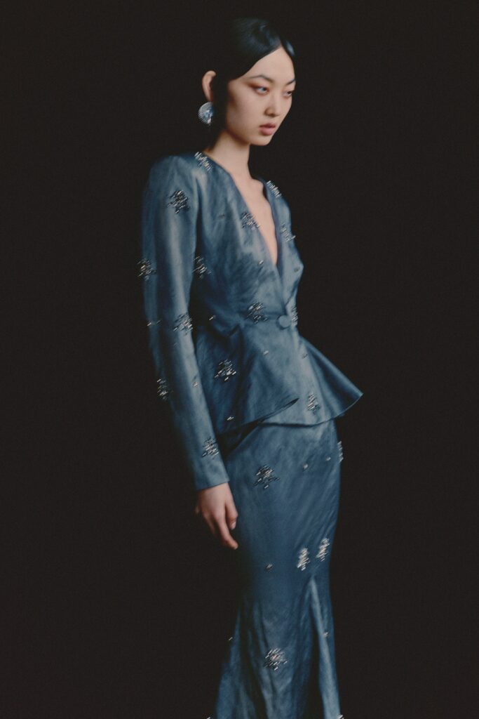 A fitted blue silk dress with long sleeves and a V-neckline in a pencil silhouette.