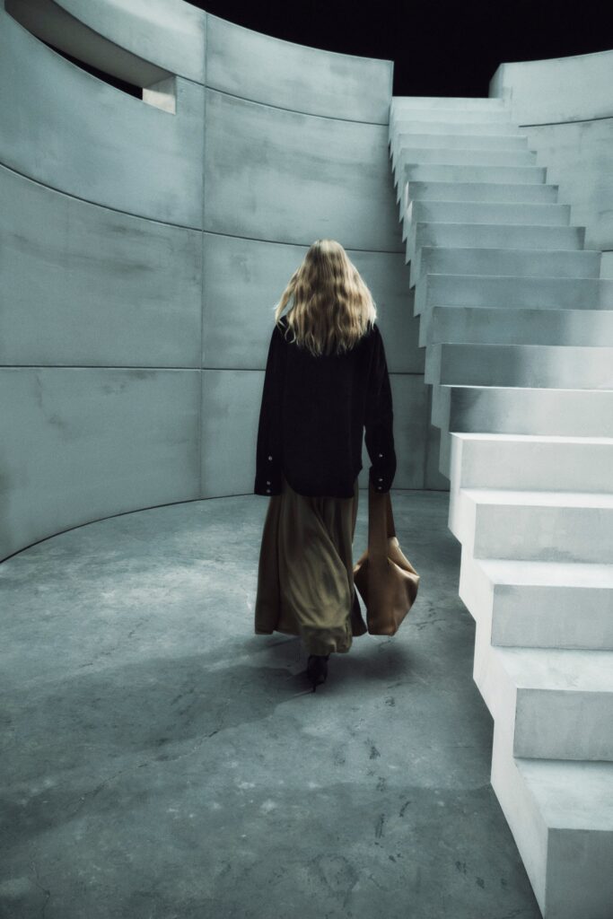 A relaxed black dress with long sleeves, a collared neckline, and an asymmetric design.