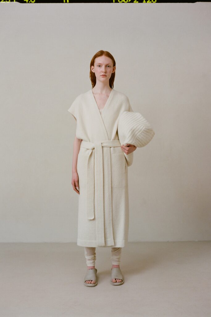 A relaxed white wool dress with a sleeveless wrap design and belted detail.