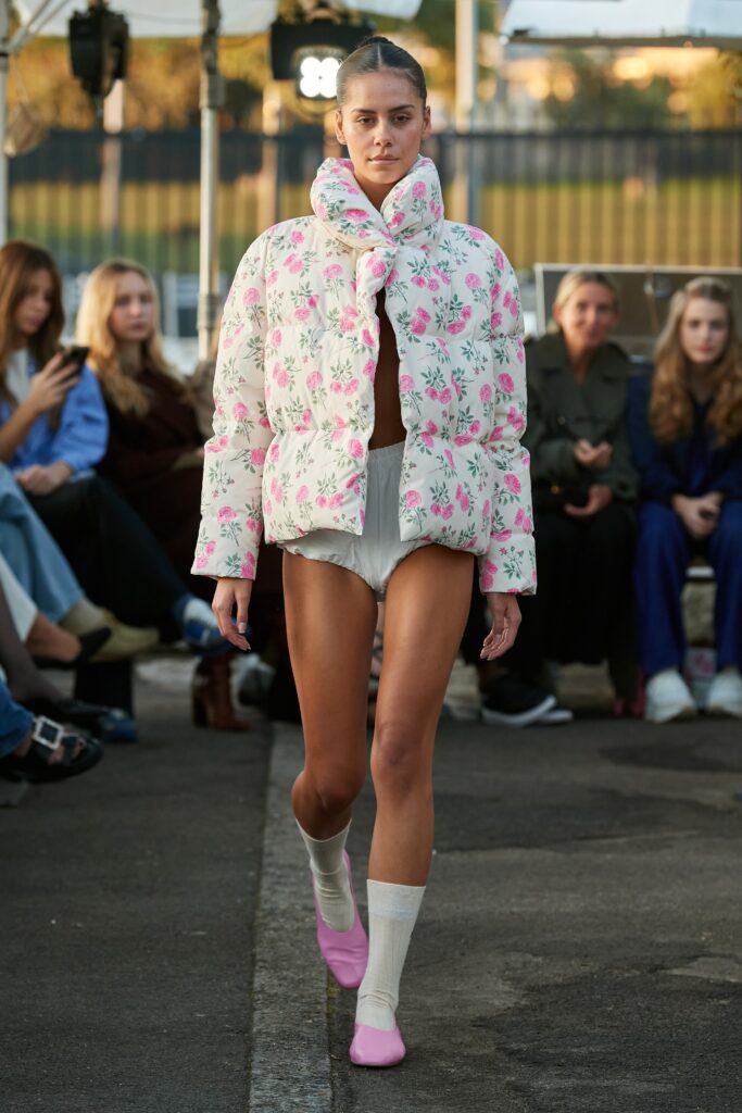 An oversized white jacket with pink floral patterns, featuring long sleeves and a collared design.