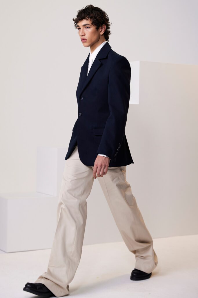 A tailored navy blazer paired with straight-leg beige pants, featuring a collared shirt underneath.