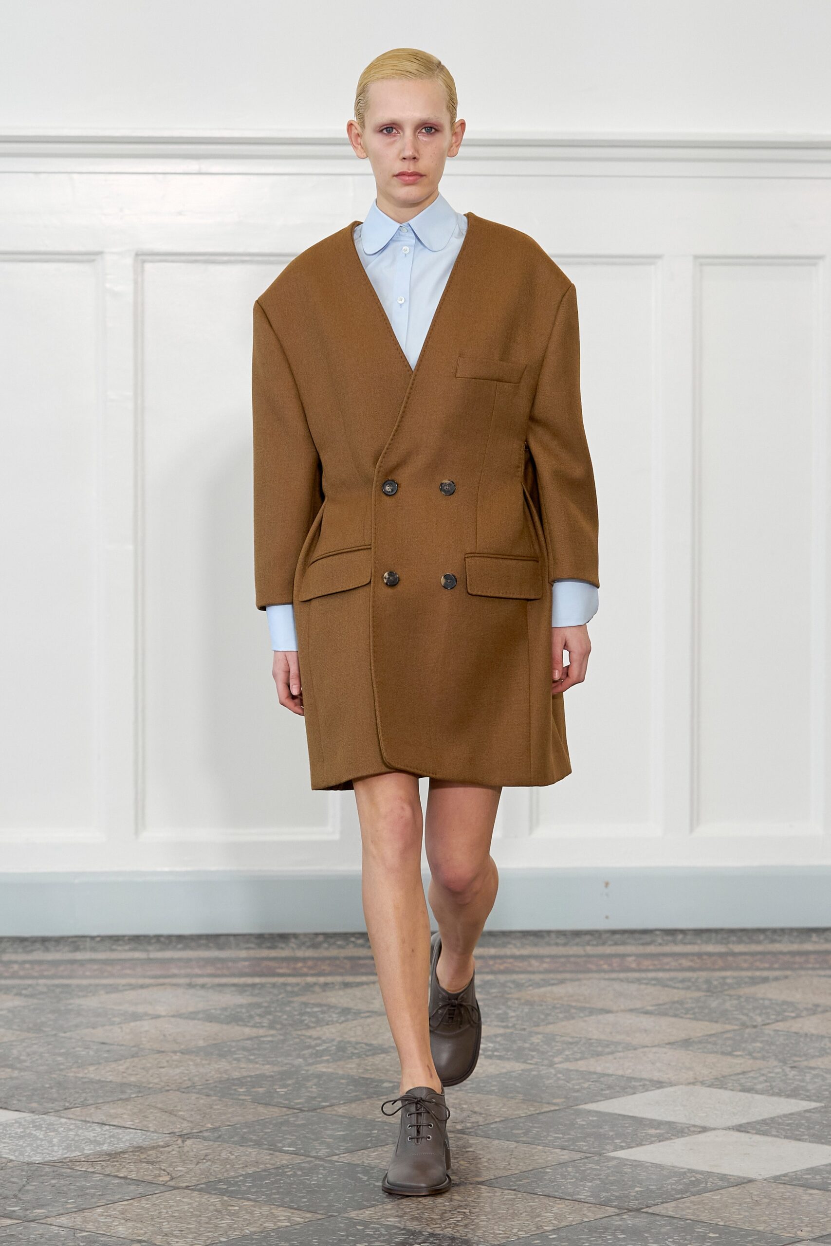 An oversized brown wool coat with a collared neckline and buttoned front.