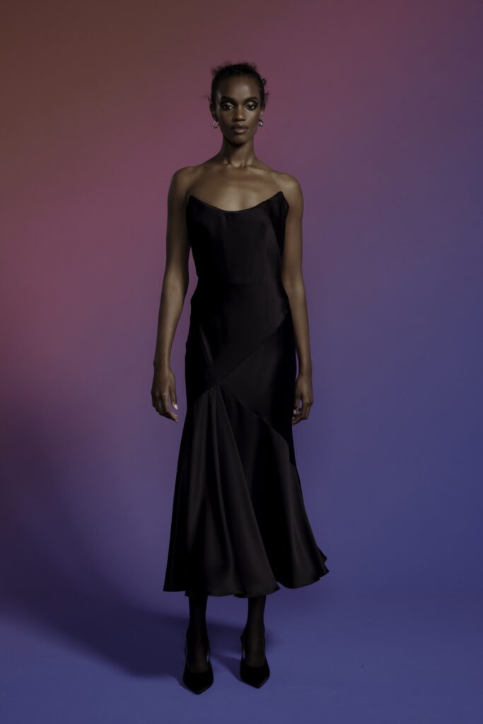 A fitted black silk sleeveless dress with a V-neckline and asymmetric design detail.