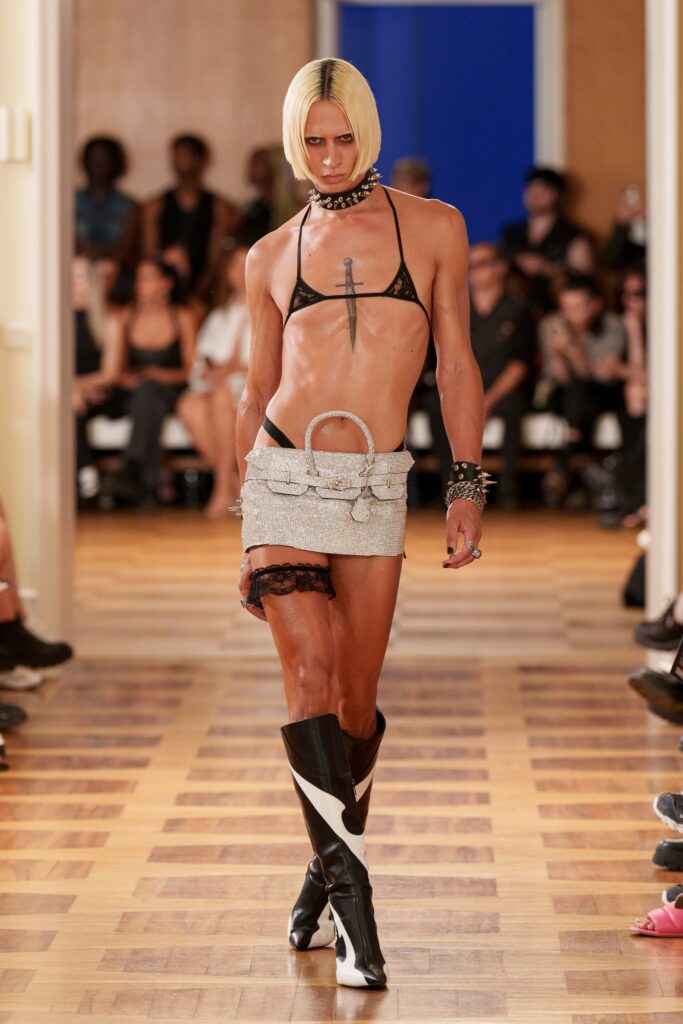A fitted black leather sleeveless top paired with a gray skirt featuring unique design elements.