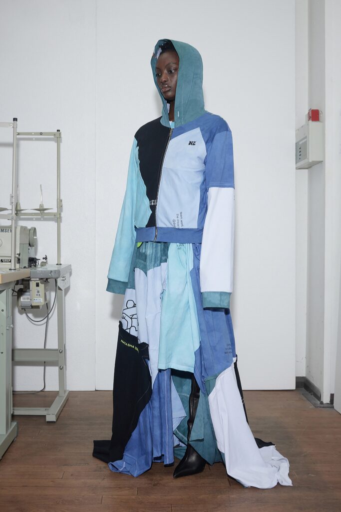 A relaxed blue dress with a hood and long sleeves, featuring an asymmetric layered design.
