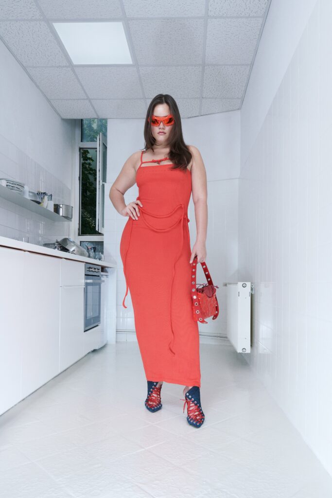 A fitted red sleeveless dress with a high neckline and a stylish slit.