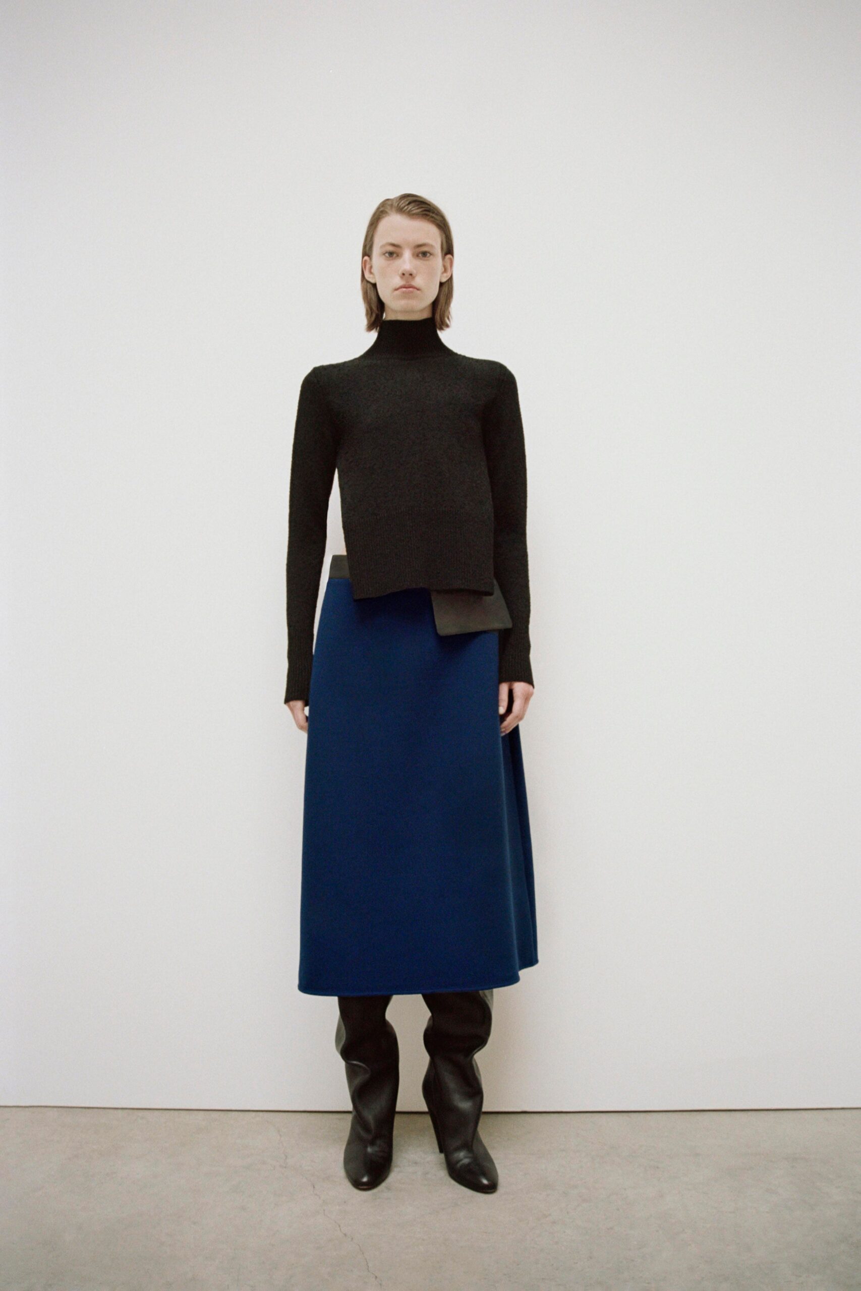 A fitted black wool long-sleeve top paired with a blue asymmetric maxi skirt.
