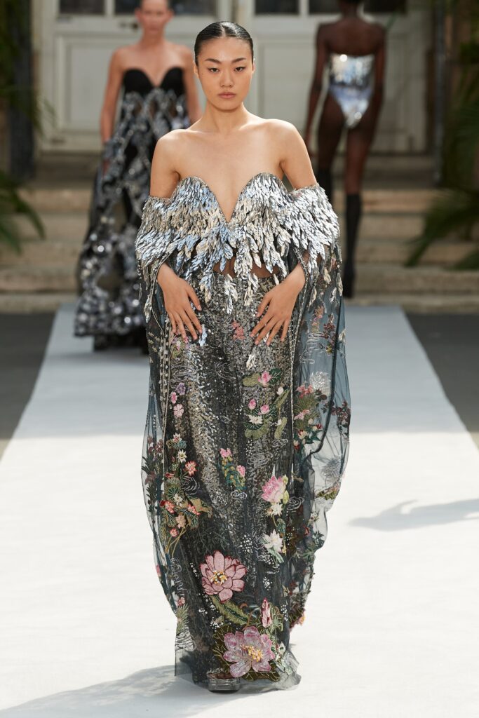 A fitted black and silver gown with a V-neckline, layered design, and intricate embroidery.