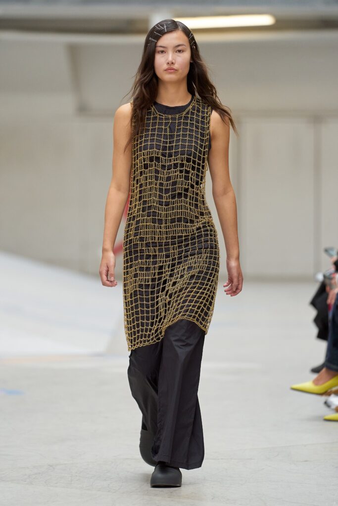 A relaxed black sleeveless dress with a V-neckline and asymmetric design detail.