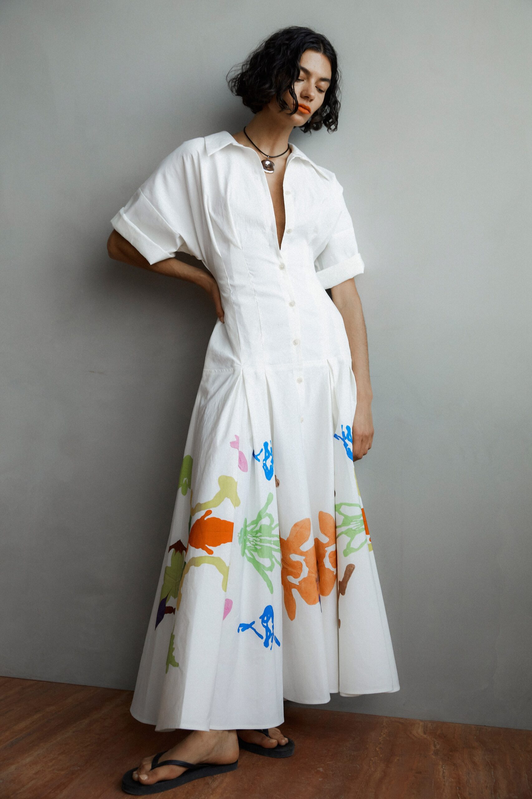 A relaxed white cotton dress with short sleeves, a V-neckline, and a tiered silhouette.