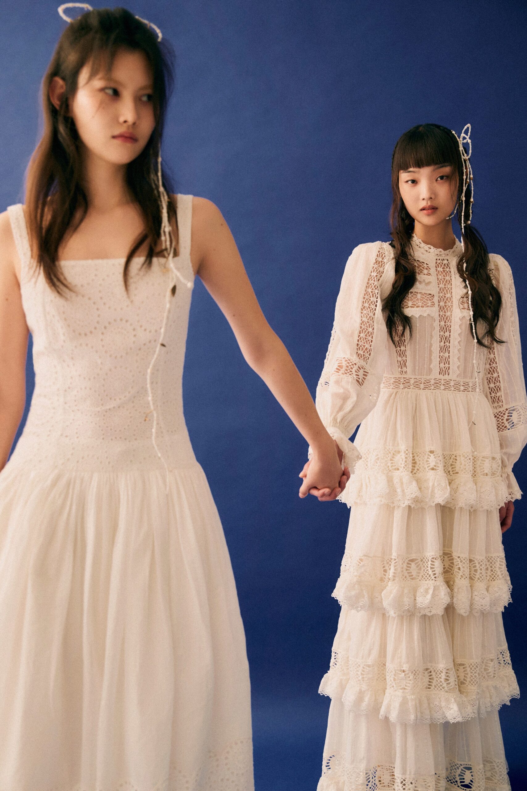 A fitted white sleeveless dress with a high neckline and tiered design.