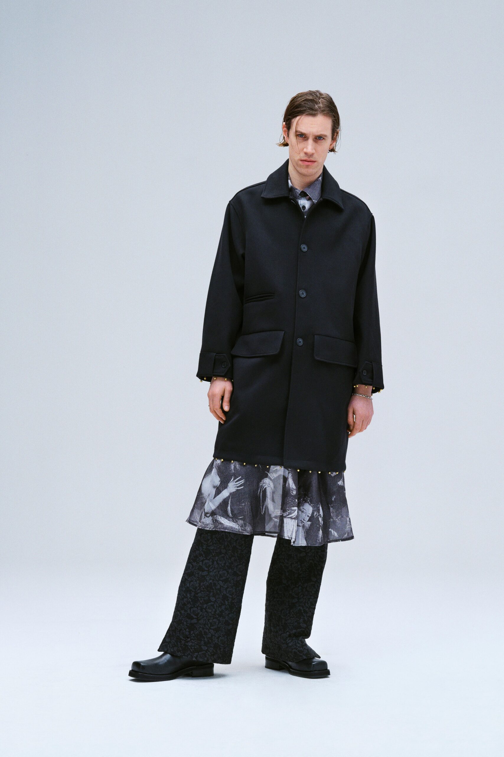 A relaxed black coat paired with gray straight-leg pants featuring a layered design.