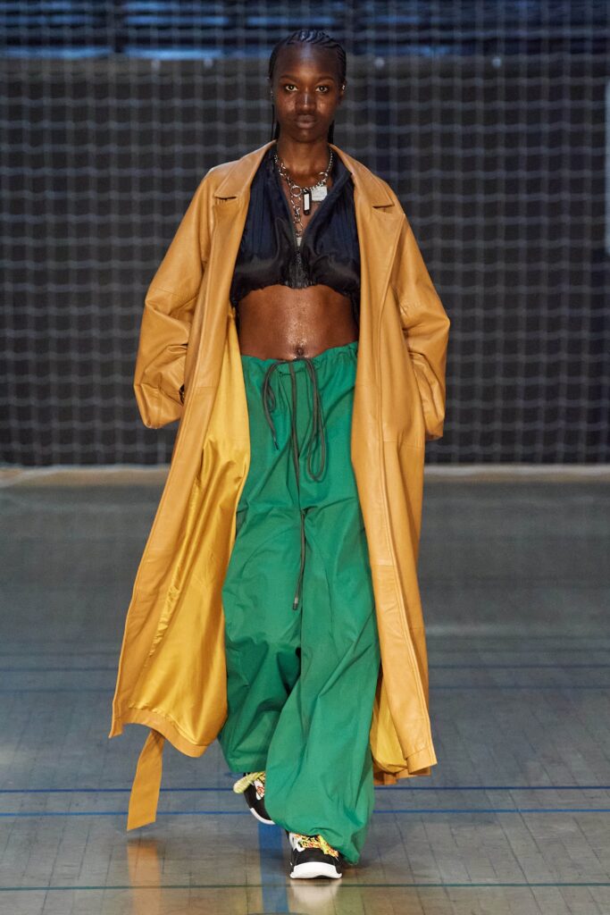A relaxed yellow leather coat paired with high-waisted green pants featuring a wide-leg silhouette.