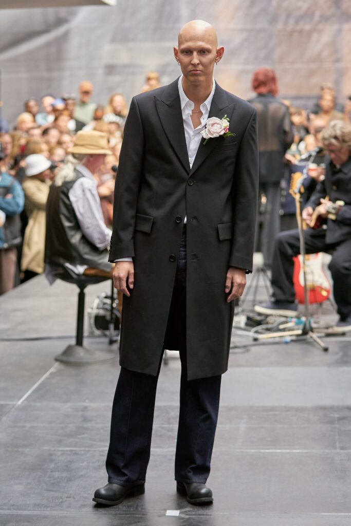 A fitted black wool coat with long sleeves and a collared neckline, paired with straight-leg pants.