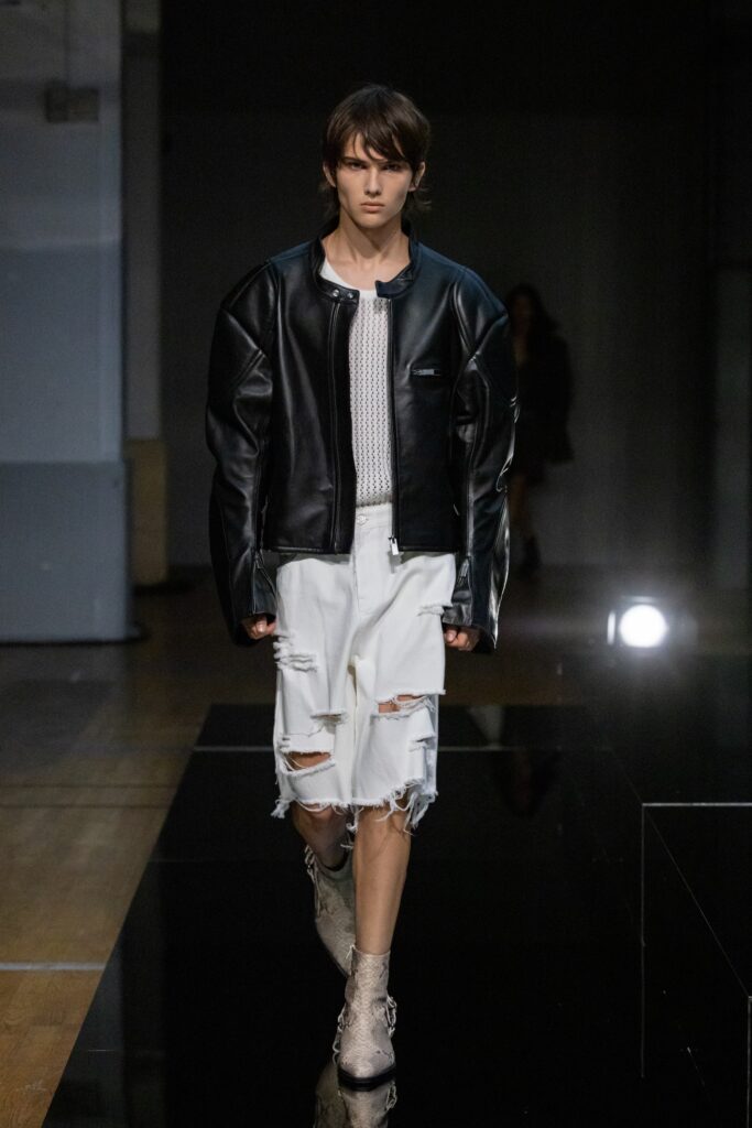 A relaxed black leather jacket paired with distressed white denim shorts.