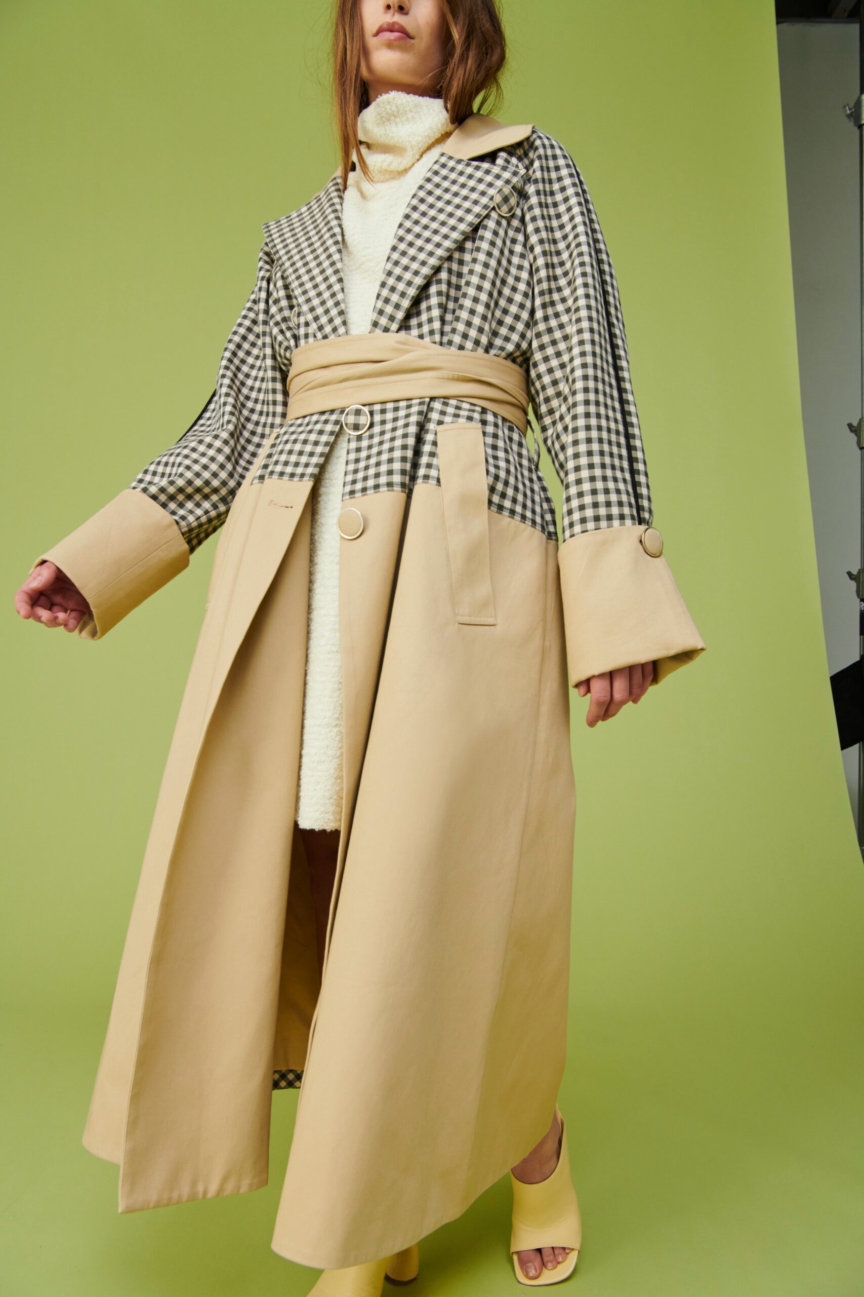 A relaxed beige coat with black checked details and long sleeves, featuring a collared design.