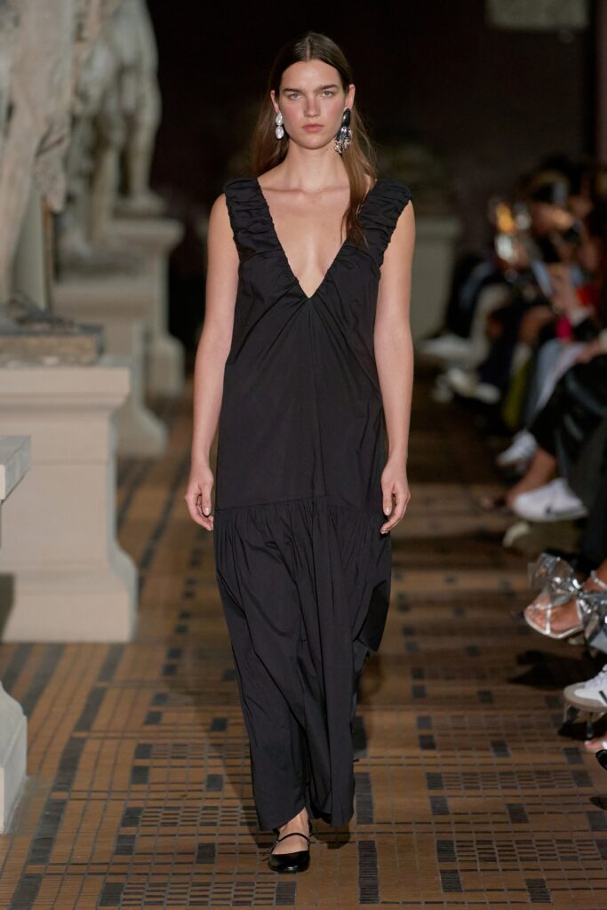 A relaxed black sleeveless dress with a V-neckline and tiered design.