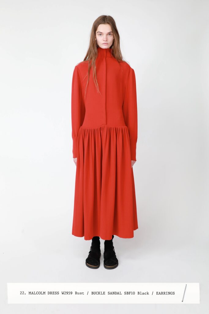 A relaxed red cotton dress with long sleeves and a high neckline featuring a tiered design.