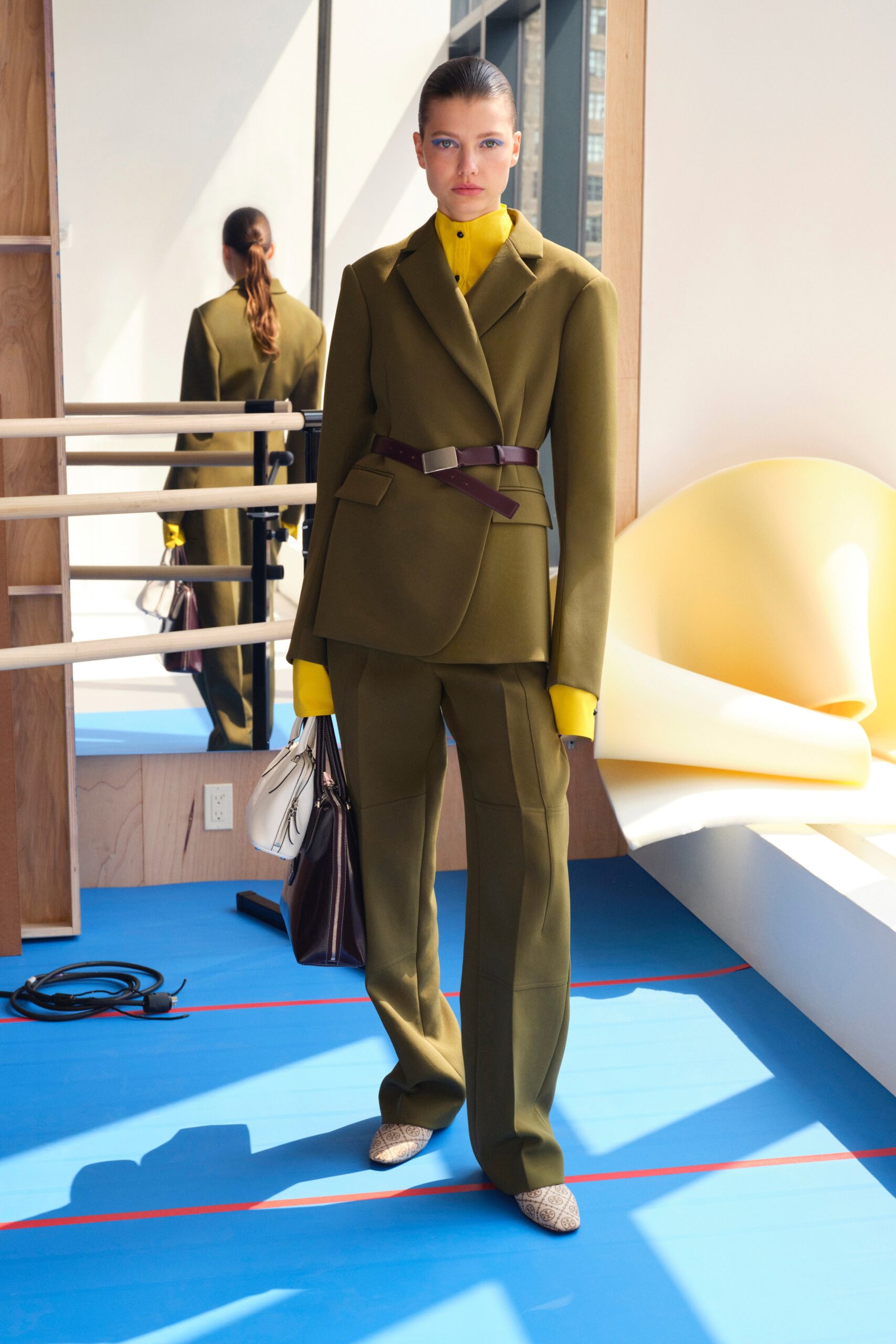 A tailored green wool suit with long sleeves and a collared design, featuring button details.