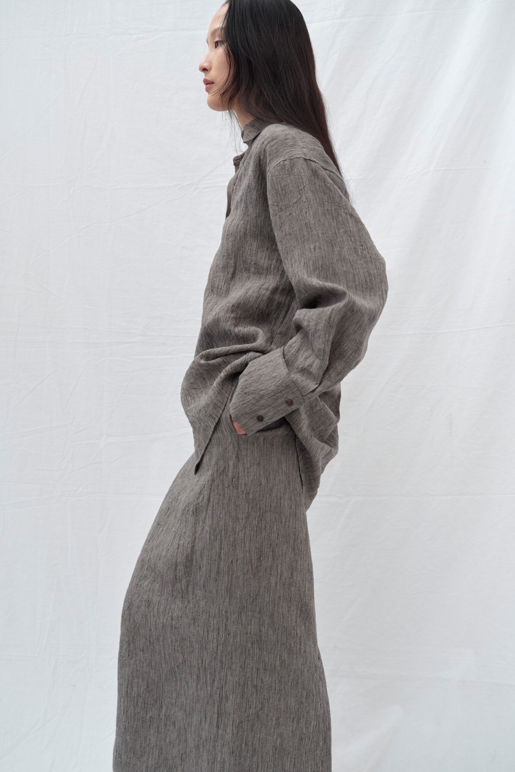 A relaxed gray cotton long-sleeve shirt paired with a straight-leg skirt.