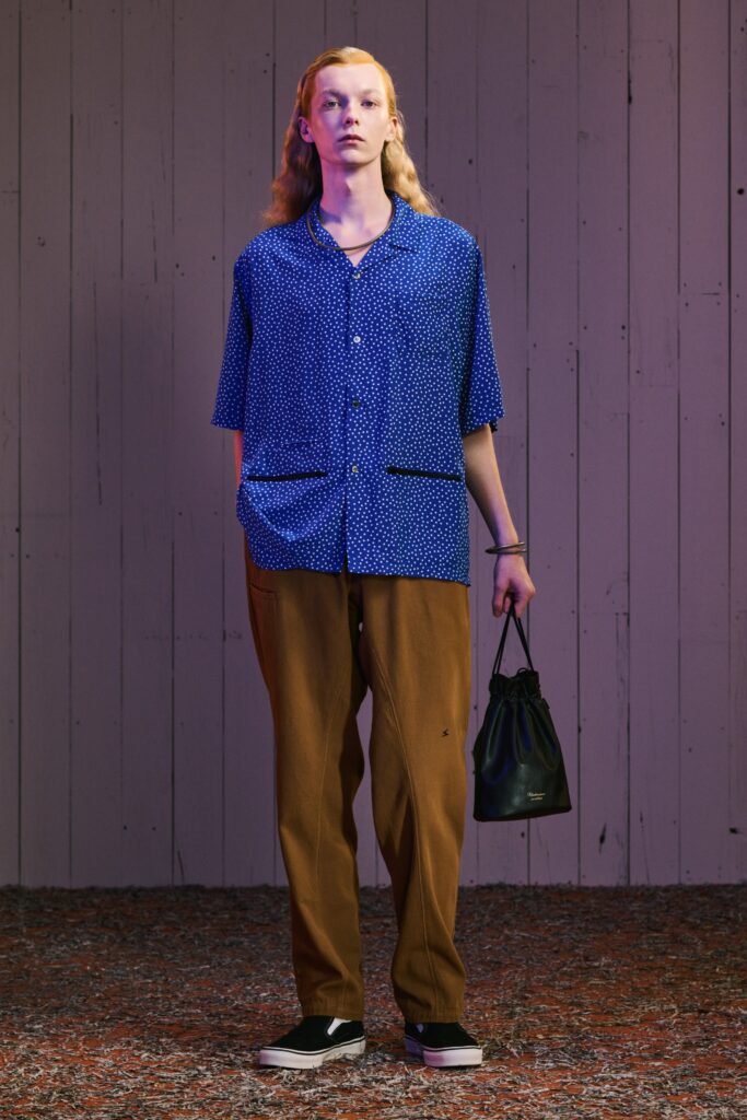 A relaxed blue printed shirt with short sleeves paired with brown pants.