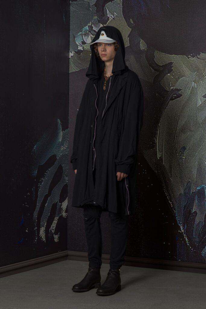 A relaxed black coat with a hood, paired with black pants, creating a layered look.