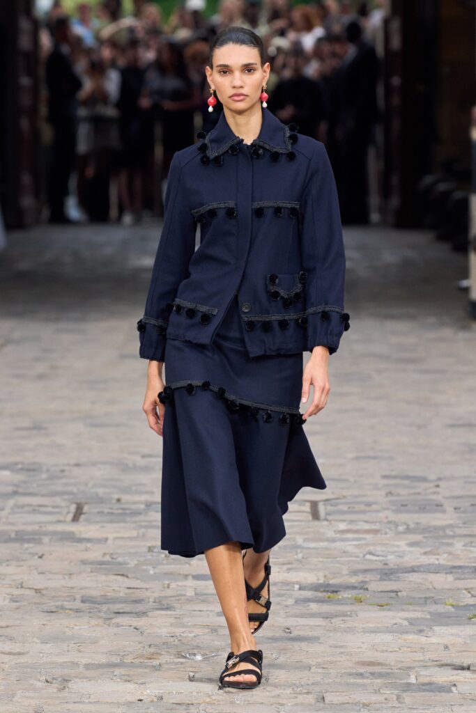 A fitted blue cotton long-sleeve dress with a collared neckline and asymmetric design details.