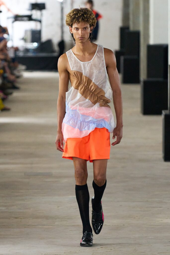 A relaxed fit sleeveless top layered over colorful shorts, perfect for a bold summer look.