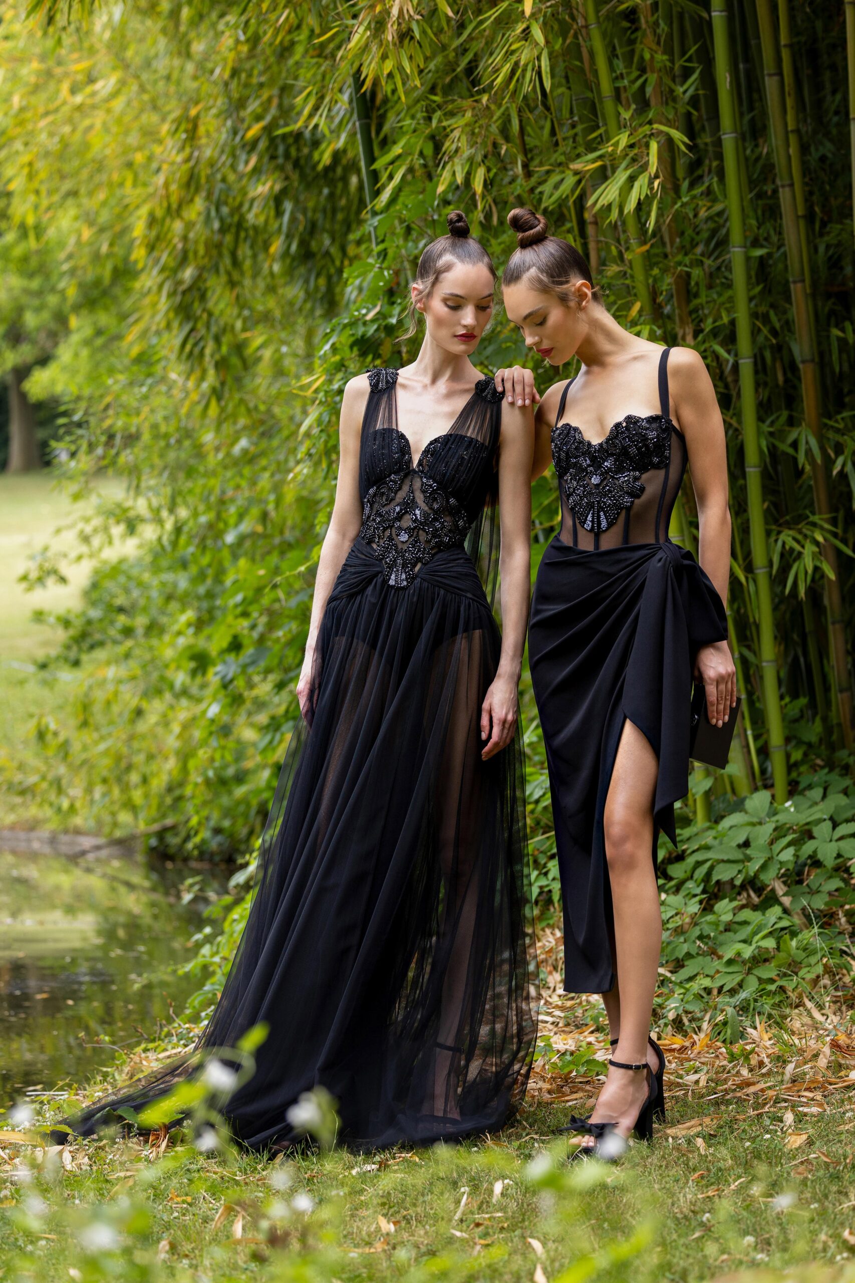 A fitted black silk dress with a sleeveless design, V-neckline, and tiered silhouette featuring a slit.