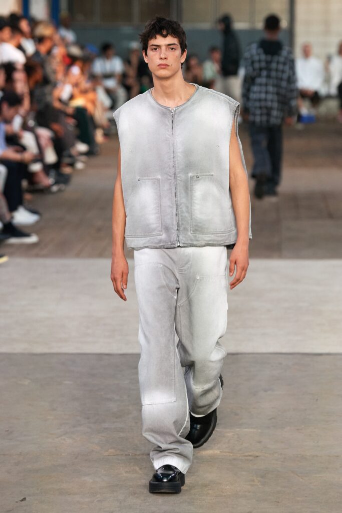 A relaxed gray denim sleeveless vest paired with straight-leg pants for a contemporary look.