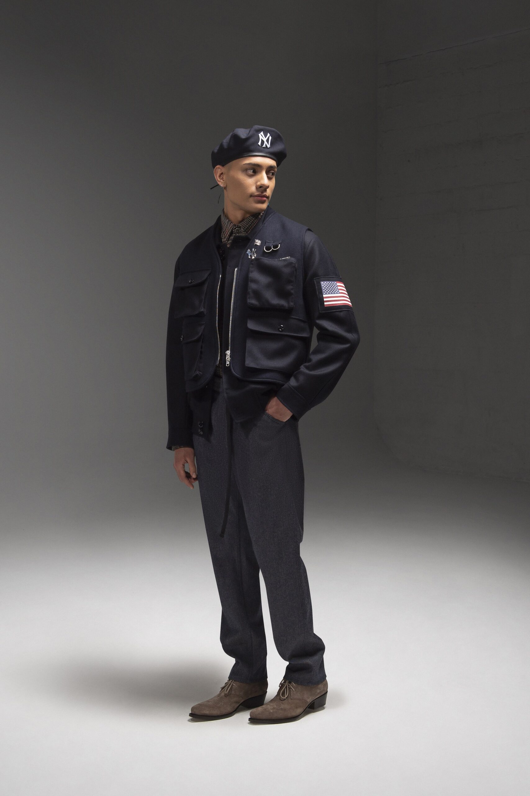 A fitted black jacket with long sleeves and a collared design, paired with gray pants.