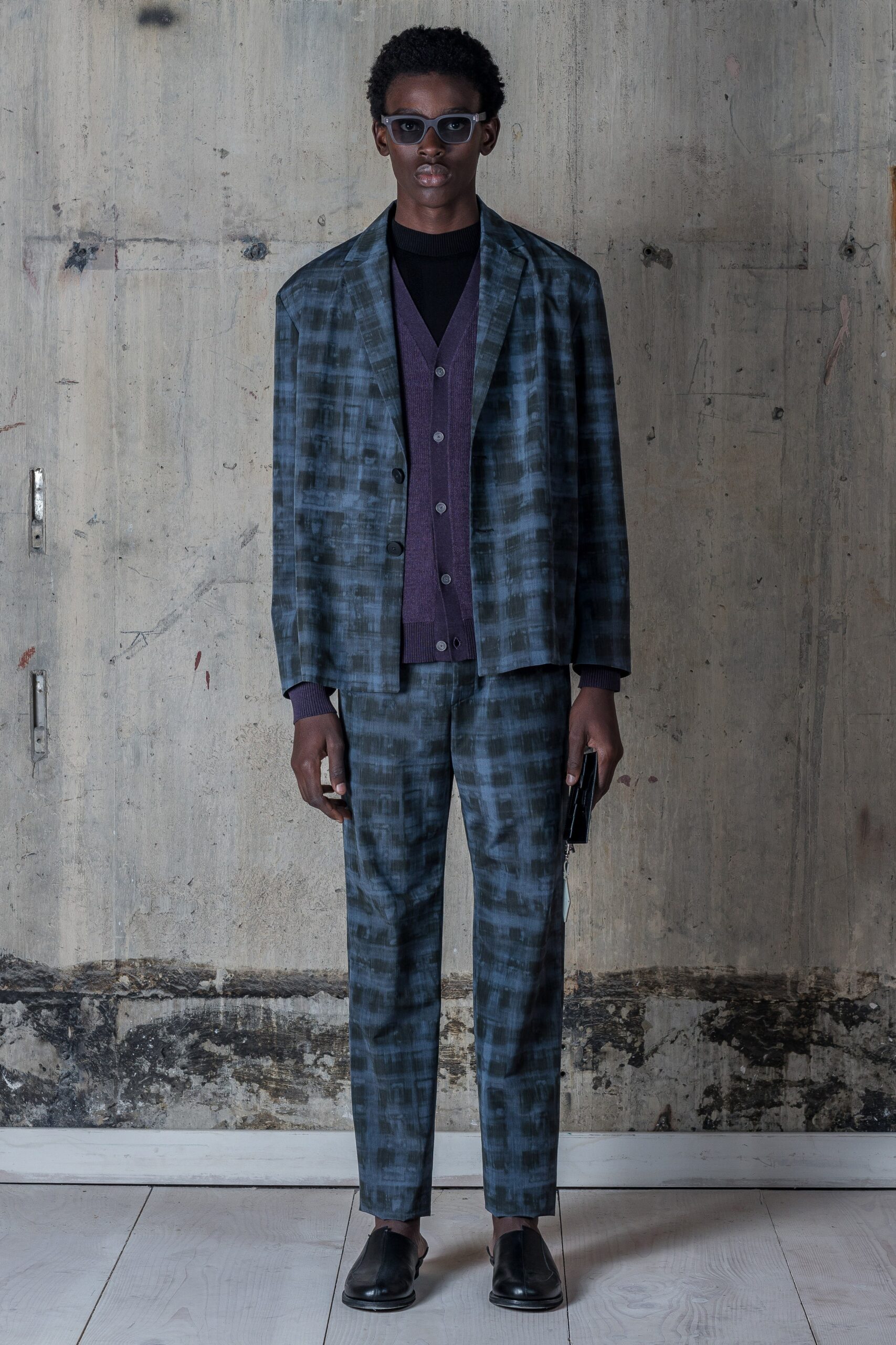 This tailored suit features a striking checked pattern in shades of blue and gray, offering a modern twist on classic menswear. The long-sleeve collared jacket complements the structured silhouette, creating a harmonious balance between formality and contemporary style.