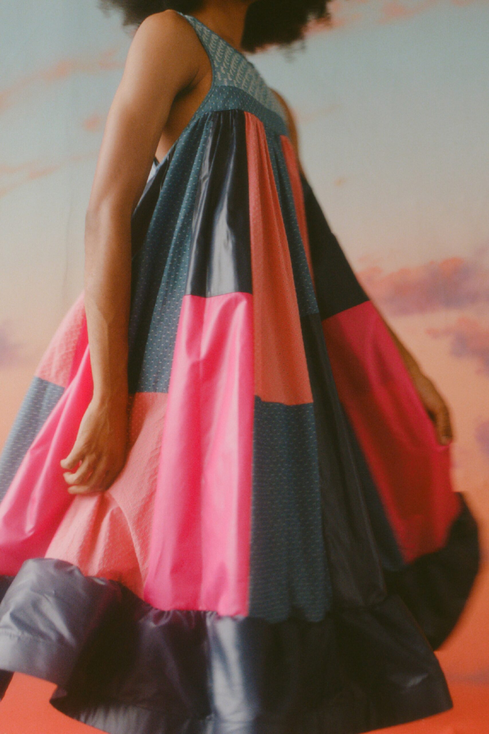 This relaxed dress showcases a playful color-blocked design, featuring vibrant hues of pink and blue. The tiered silhouette adds movement and depth, while the high neckline offers a contemporary twist to a classic shape.