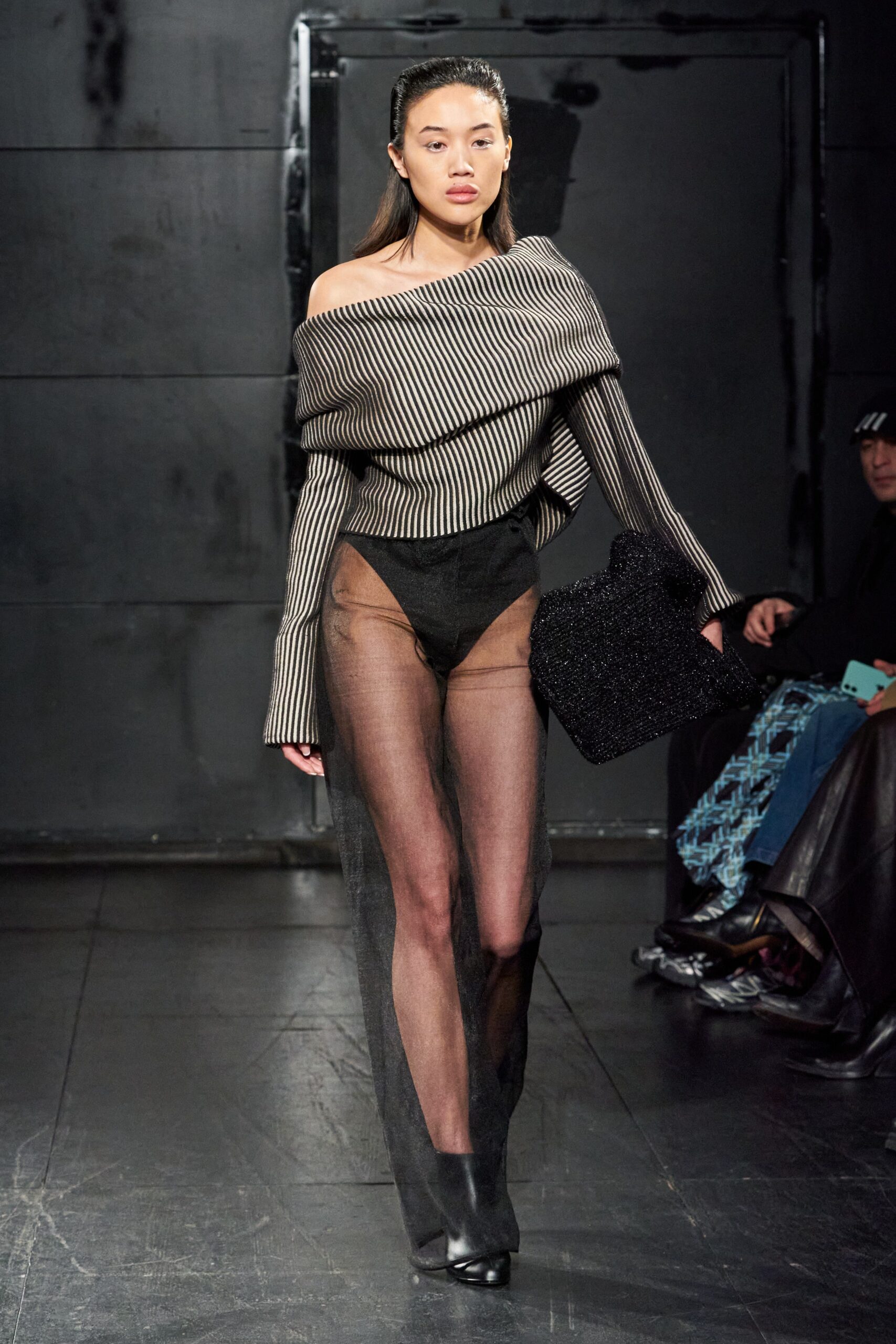 A fitted black sheer off-shoulder top with long sleeves paired with fitted sheer pants.