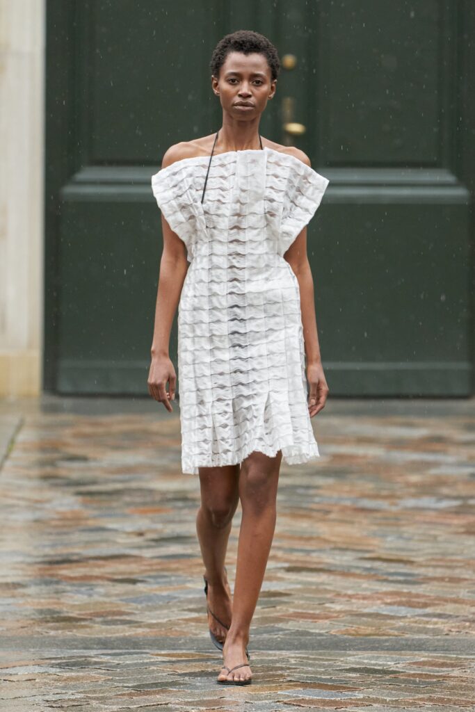 A fitted white cotton off-shoulder dress with ruffled and tiered details.