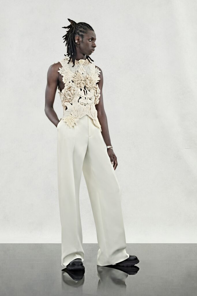 A relaxed beige embroidered sleeveless top paired with wide-leg white pants.