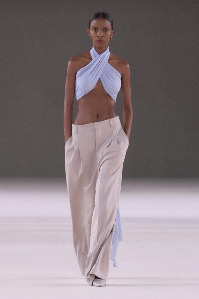 A relaxed blue sleeveless top paired with wide-leg beige pants for a chic look.