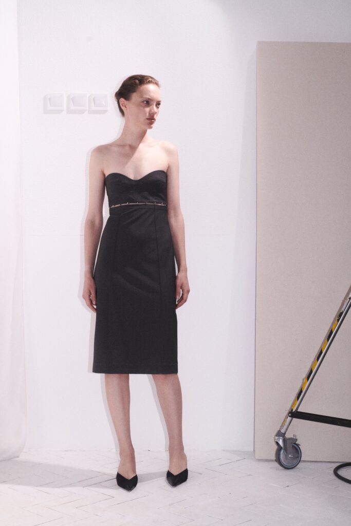 A fitted black strapless dress with a V-neckline and pencil silhouette.