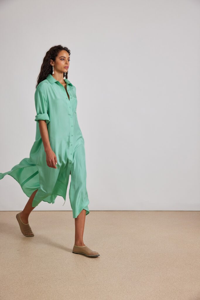 A relaxed green silk dress with long sleeves and a collared neckline featuring buttoned and tiered details.