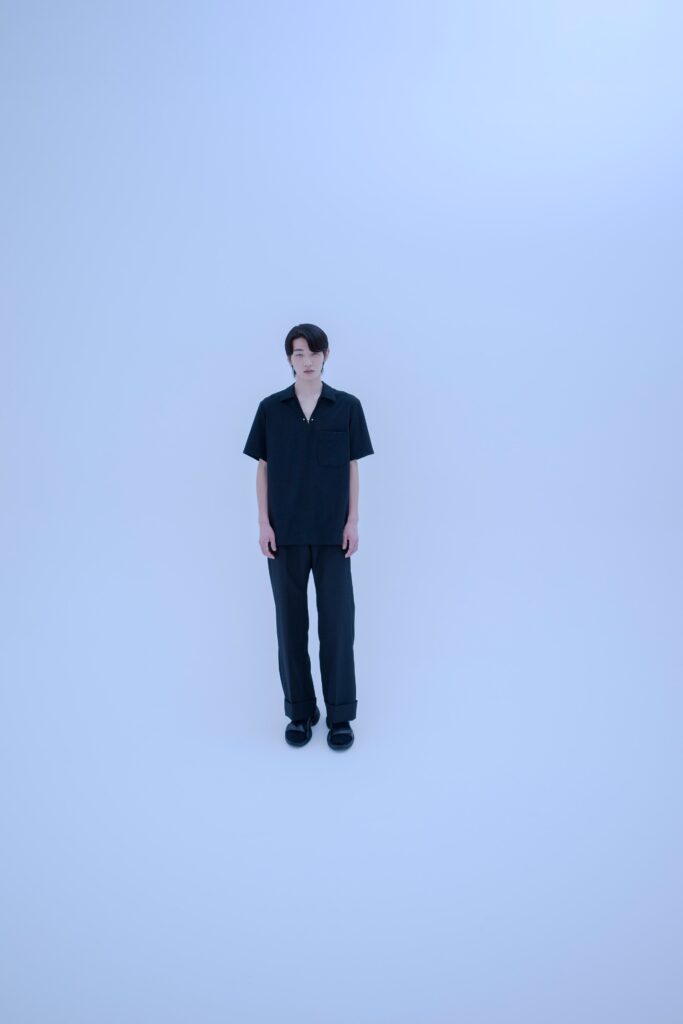 A relaxed black shirt with short sleeves and a collared neckline paired with straight-leg pants.